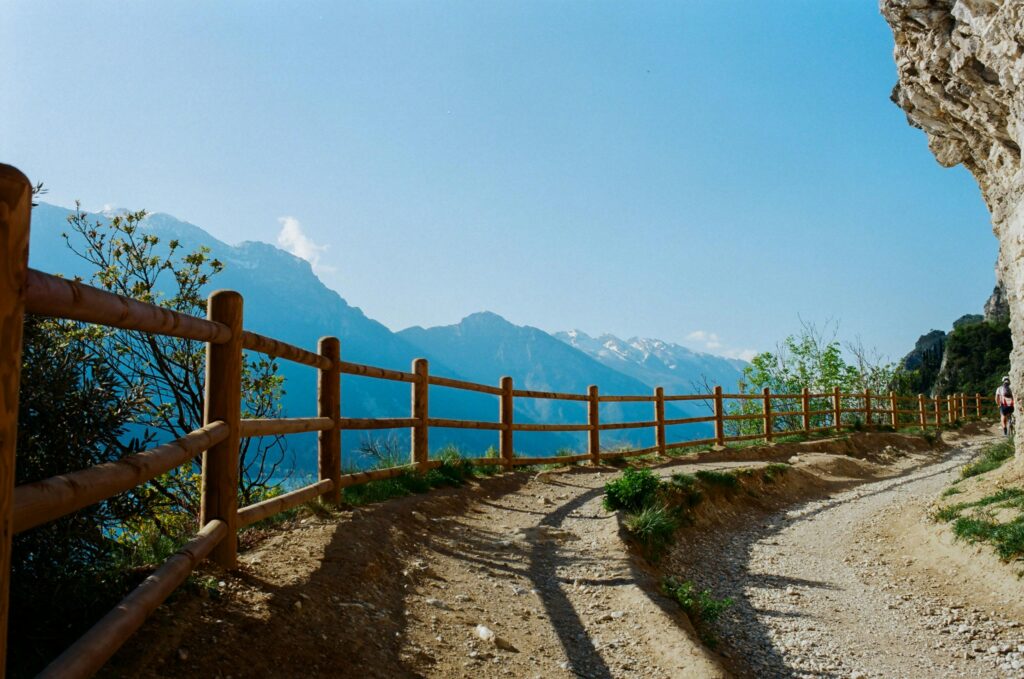 A tranquil mountain pathway in Italy surrounded by wooden fences and stunning views.